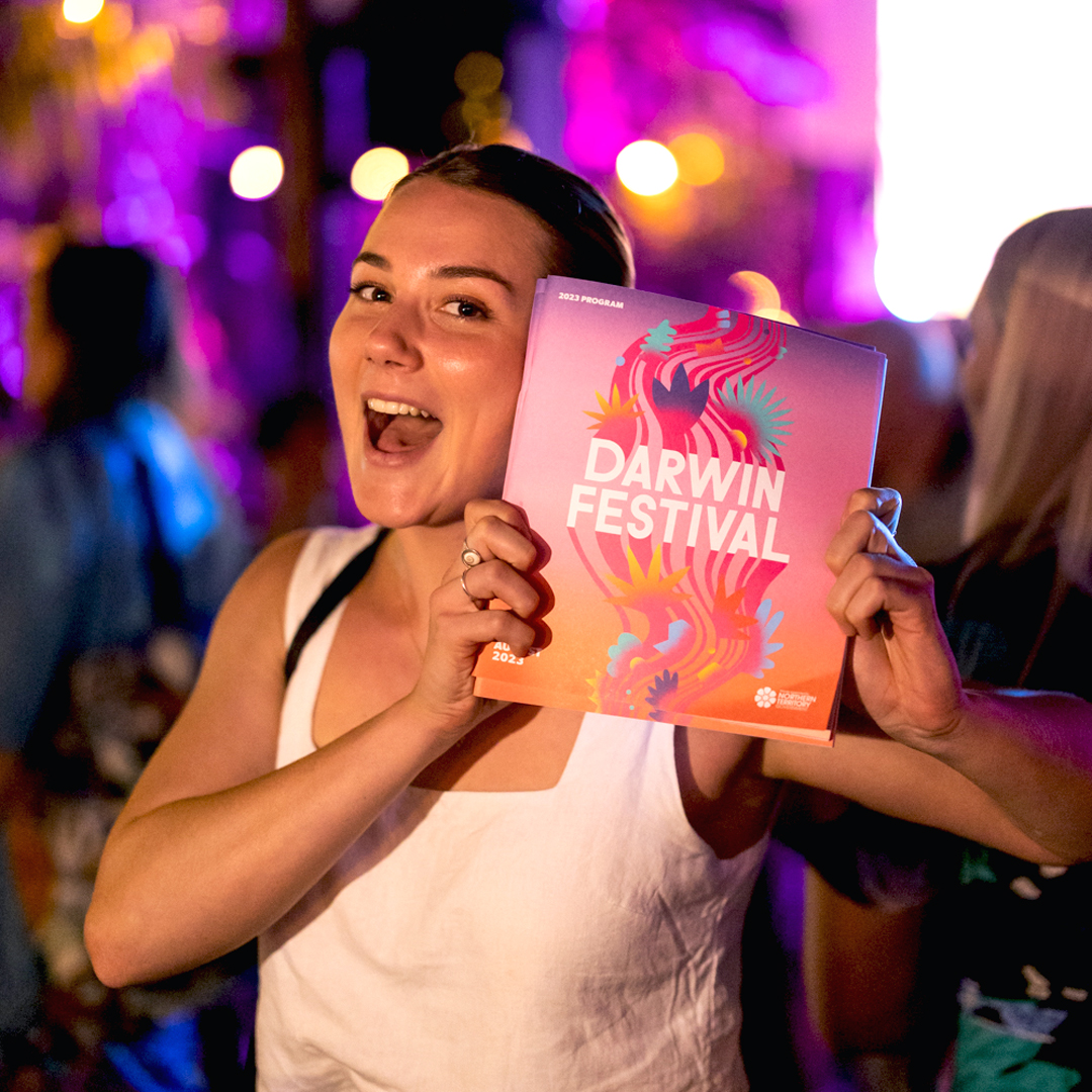 Woman holding a Darwin Festival magazine, design by kwpx